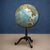 This 20th Century American Metal and Paper Raised Relief Globe is a striking decorative object that blends educational...