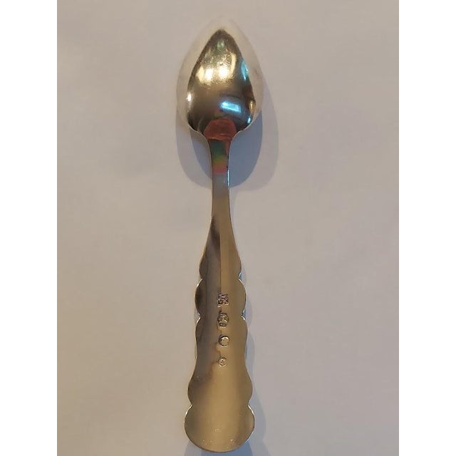 Antique Dutch silver teaspoon featuring a plain oval bowl and a distinctive scalloped handle. The maker's punch appears...