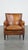 This subtle cognac-colored sheep leather armchair with a nice design and finish with black piping and decorative nails. A...