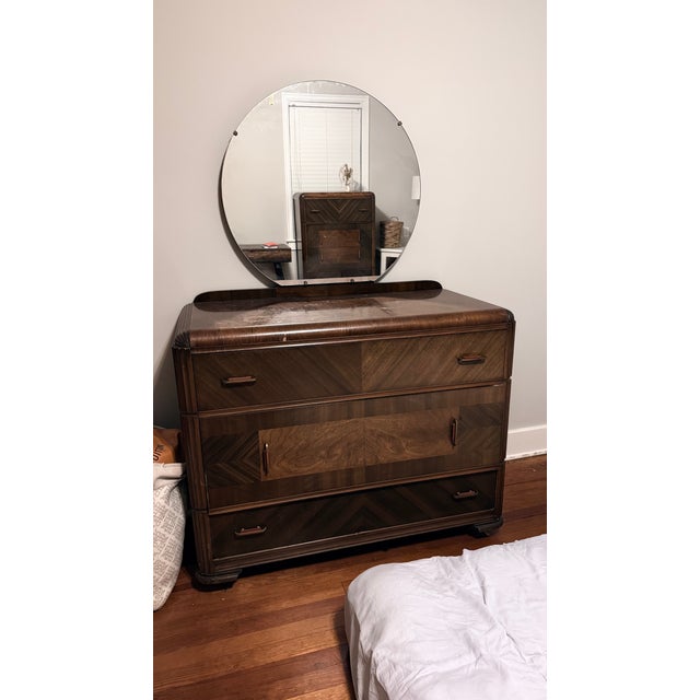 The Art Deco Lowboy Dresser with Mirror features the sleek lines and geometric shapes characteristic of the Art Deco...