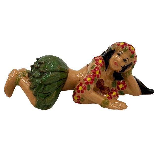 Mid-century Era Aloha Hula Girl Lying down Ceramic Figurine w/ Red Flowers & green grass skirt. The statue features a...