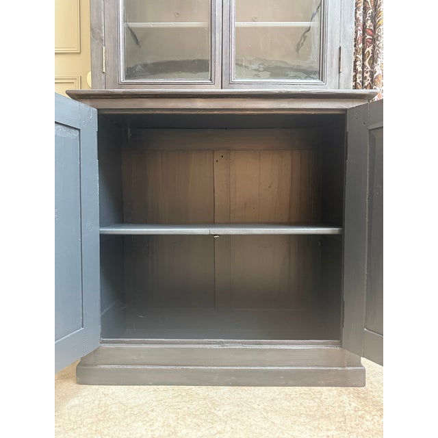This antique two-piece pine sideboard captivates with its clean, timeless lines. Its deep black patina highlights its...