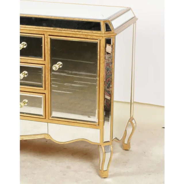A glamorous Hollywood Regency-style sideboard enveloped in beveled mirrored-glass panels and framed in a warm antiqued-...