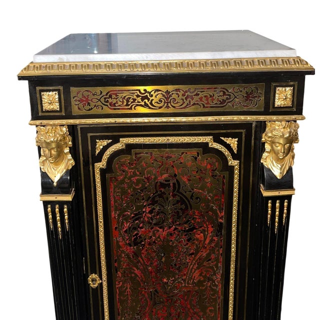A striking 19th century French Boulle-style cabinet crafted in ebonized wood with elaborate gilt bronze mounts and a white...