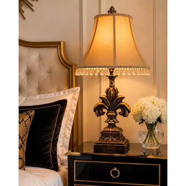 A striking pair of French Provincial-inspired table lamps featuring sculptural fleur-de-lis forms, architectural pedestal...