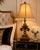 A striking pair of French Provincial-inspired table lamps featuring sculptural fleur-de-lis forms, architectural pedestal...