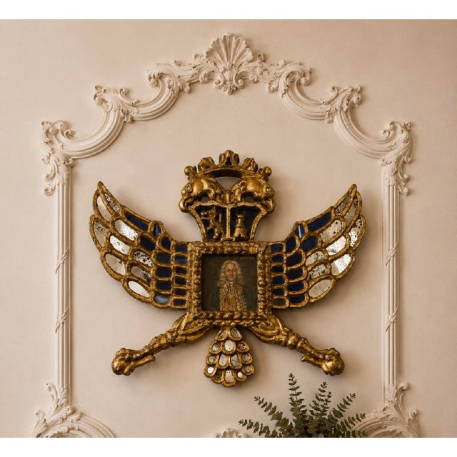 A striking Spanish Colonial giltwood heraldic-form mirror frame dating to the late 18th or early 19th century. The...
