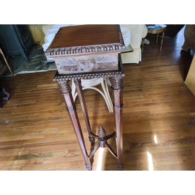 This is a carved mahogany pedestal plant stand, styled closely after classical English revival or Victorian furniture...