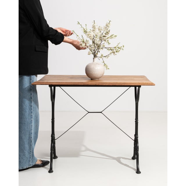 An authentic French bistro table combining a sturdy cast iron base with a warm oak top. The contrast of materials creates...