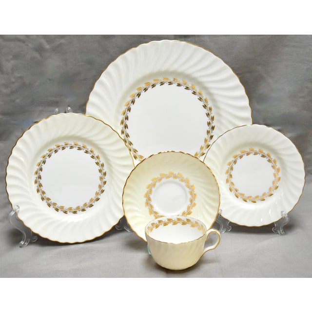 A 1950s graceful Minton bone china dinner service having a soft cream outer bands that have a swirling concave flutes,...