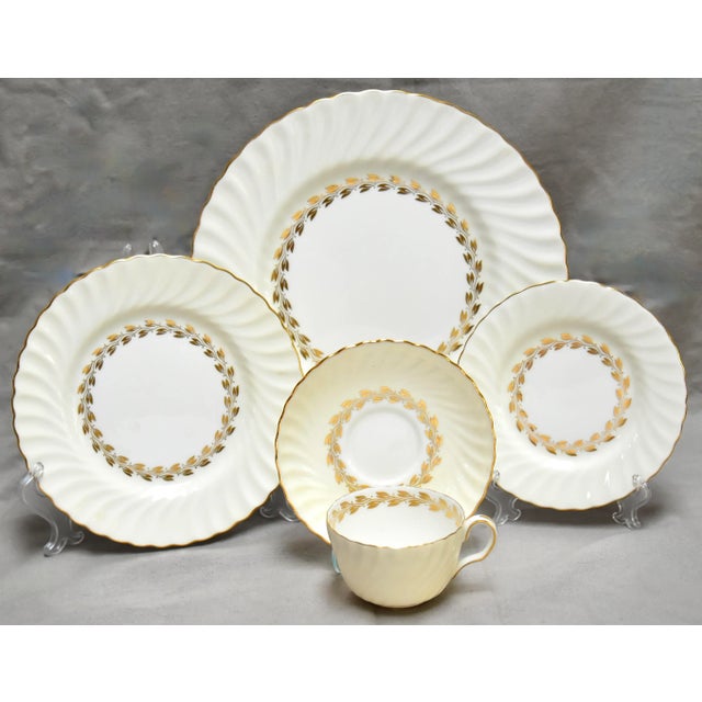A 1950s graceful Minton bone china dinner service having a soft cream outer bands that have a swirling concave flutes,...