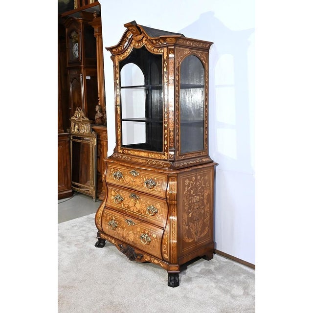 Meuble en deux éléments, composé en partie basse d’une commode dont la façade à mouvement est richement ornementée. Trois...