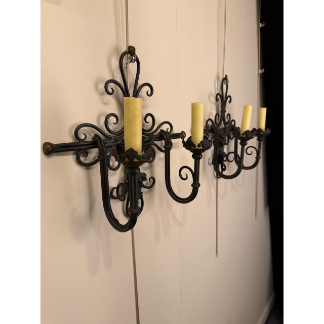 Pair of 19th-century Belgian two-arm iron sconces dating to circa 1890. The sconces feature a decorative central acanthus...
