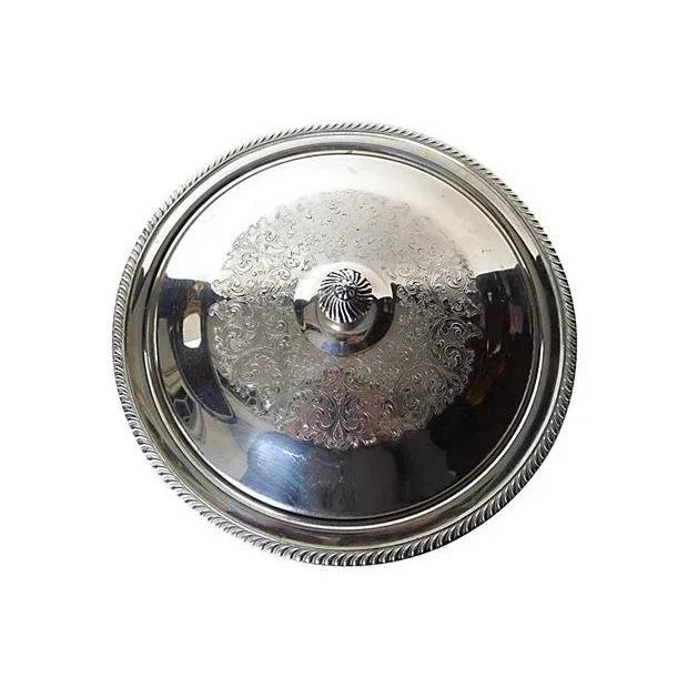 Covered and footed silverplate serving bowl with ornately decorated top. Maker's mark reads "Fiesta Oneida."