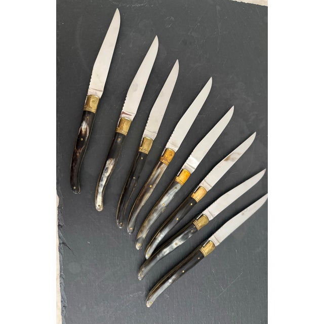 Unusual set of eight vintage Laguiole steak knives with stainless steel blades, brass bolsters and natural horn curved...