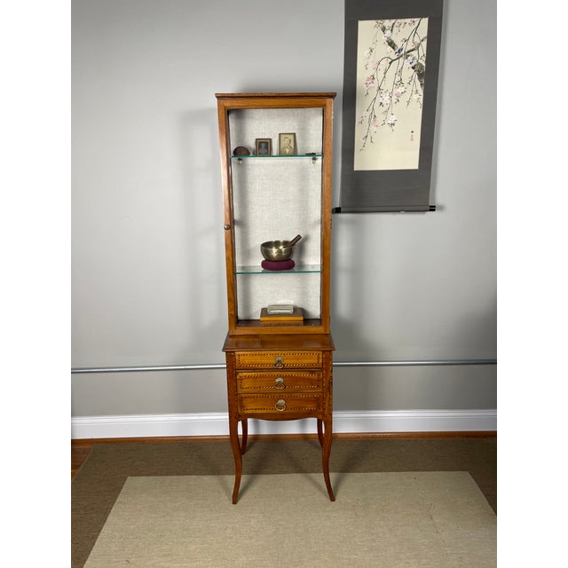 This small-scale display cabinet exhibits the rustic elegance of French provincial furniture, blending Rococo and...