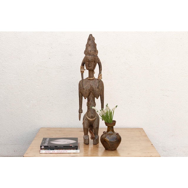 Among the Bamana people of southern Mali, a seated or standing mother figure carrying a child at her waist or back is...
