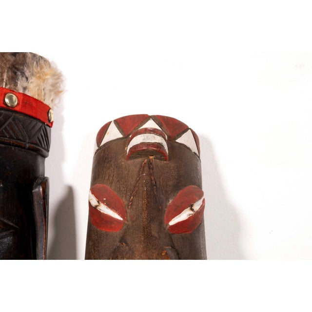 A captivating pair of African tribal masks. Hand carved wood and hand painted with feathers. In good vintage condition....