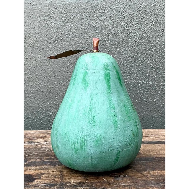 This vintage decorative pear is a plump, sculptural fruit modeled in plaster and finished in a soft, chalky green. The...