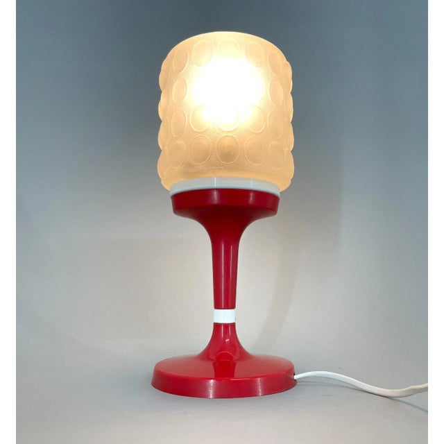 Vintage table lamp made of red and white plastic and glass. Produced by Elektroinstala Jílové in Former Czechoslovakia in...