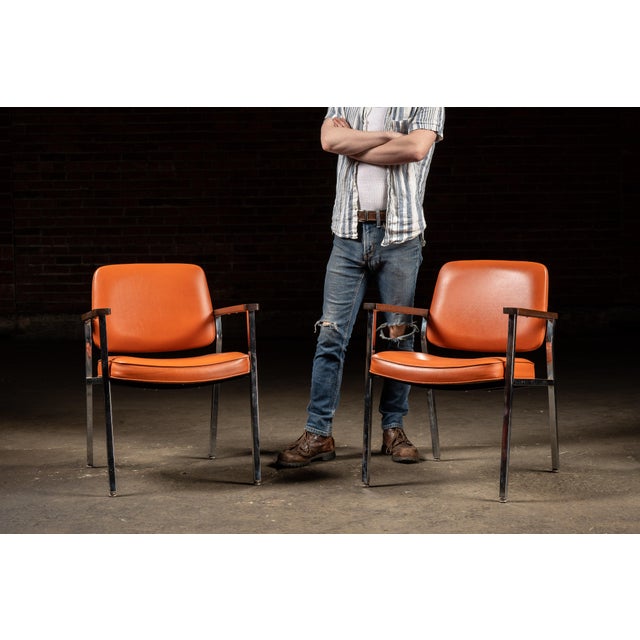 Pair of mid-century modern armchairs by Delwood Manufacturing Co. of Chicago, featuring vibrant orange vinyl upholstery...
