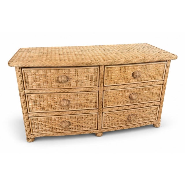 A vintage six-drawer dresser crafted in natural woven rattan, featuring a richly textured wicker top, braided framing, and...
