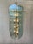 A striking modernist chandelier featuring sixteen clear beveled glass panels with a subtle green tint along their...