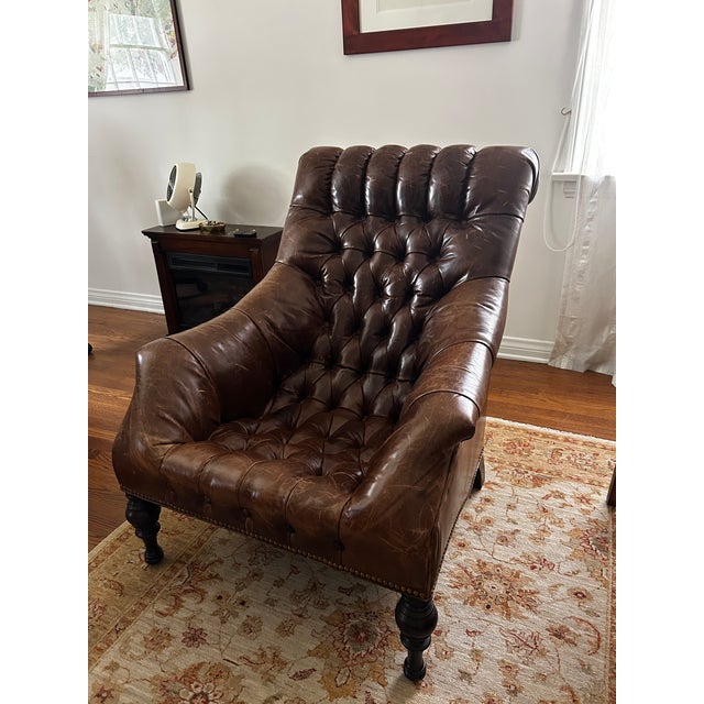A big, generous leather chair built for sinking into with a book and a glass of wine. Deep diamond tufting covers the seat...