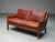 A rare and characterful loveseat by Danish designer Kai Lyngfeldt Larsen, upholstered in its original cognac leather. The...