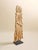 This vintage carved teak sculpture features an elongated carved form set on a black metal base. The draped, fabric-like...