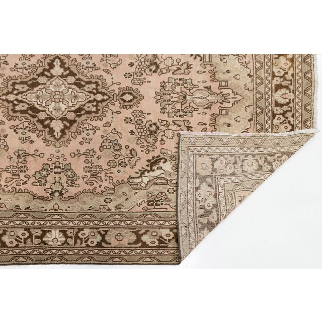 Elevate your interior space with this exquisite vintage hand-knotted wool rug, featuring a sophisticated muted palette of...