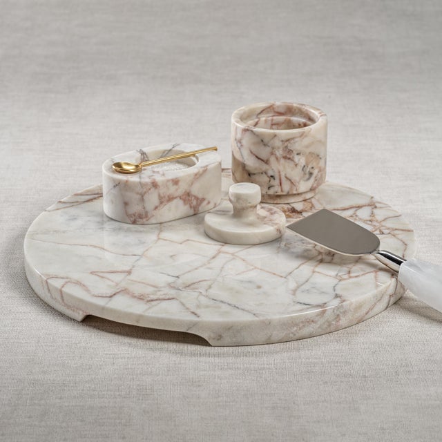 A solid slab of white marble with its smooth, substantial design features a round shape accentuated by natural, unique...