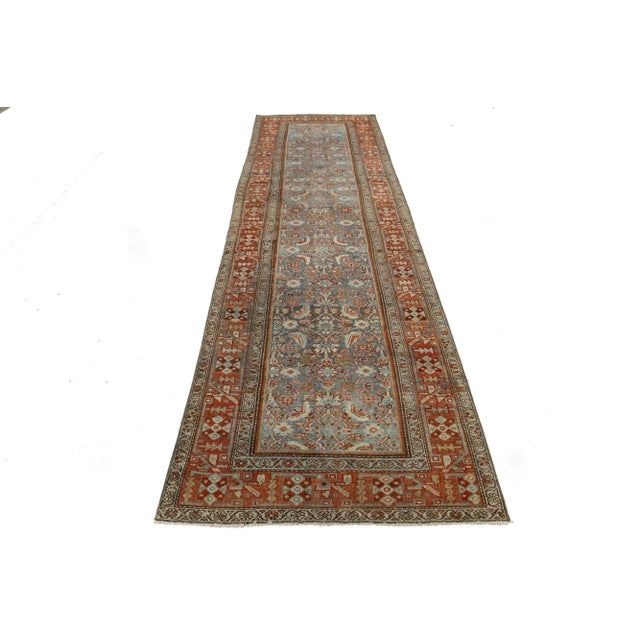 This is a handmade Persian Malayer wool rug from the 20th century. It features a blue field with rust and beige accents...