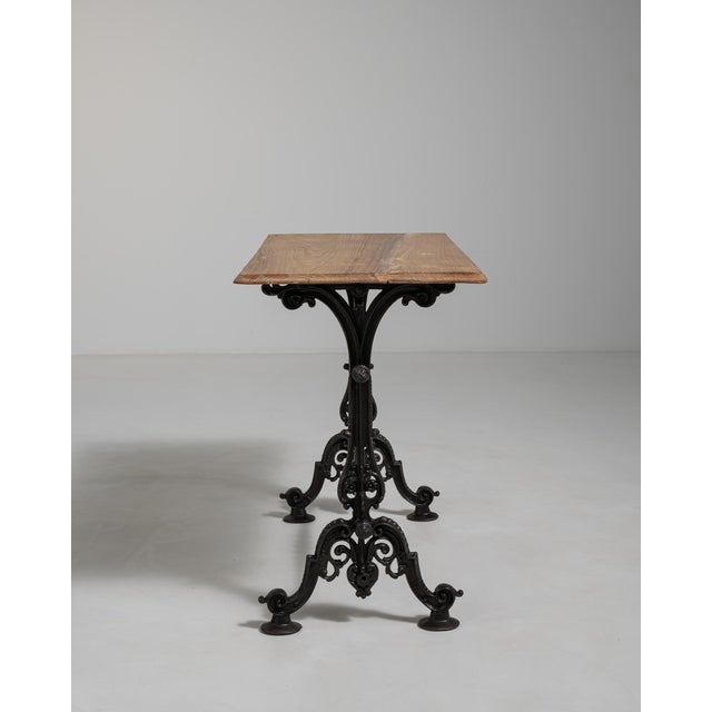 A sturdy bistro table with an ornate cast iron base reflecting Victorian craftsmanship. The durable construction ensures...