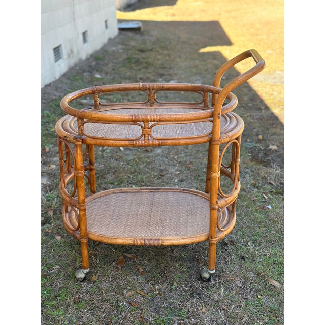 This is a vintage rattan bar cart / tea trolley, a classic coastal piece with a light, airy presence. It features a...