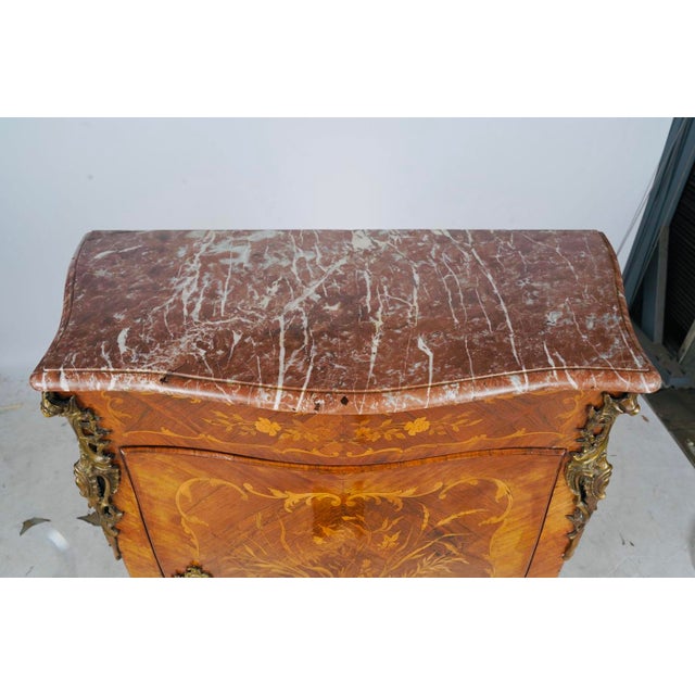 An exceptionally decorative French cabinet with lavish floral marquetry, beautifully bowed sides, a rouge marble top, and...