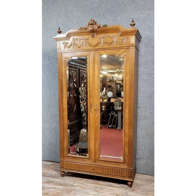 Louis xvi style mirrored wardrobe in walnut with a light patina, circa 1880. the front opens with two beveled mirrored...
