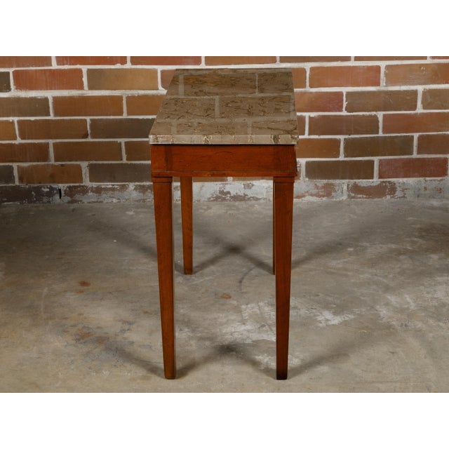 A French walnut console table from the 19th century with rectangular variegated marble top, single drawer and tapered...