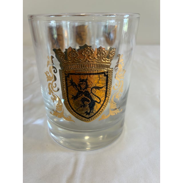 A stylish set of eight vintage lowball glasses decorated with gold heraldic crest motifs and ornate scrollwork. The...