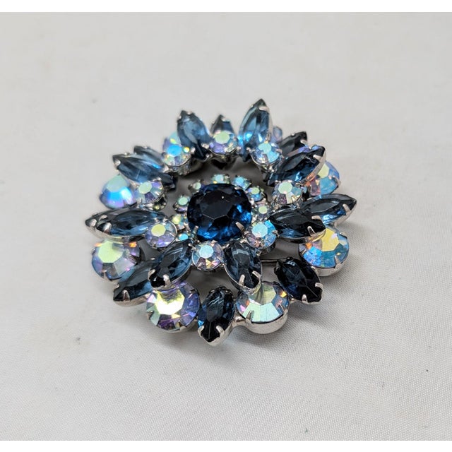 1960s rhodium plated round unfoiled faux-sapphire center surrounded by small round aurora borealis surrounded by two rings...
