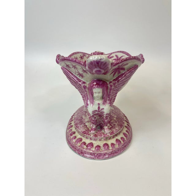 Intricately hand painted pink glazed porcelain bowl with two sphinx figures on each side. The intricate paintings depict...