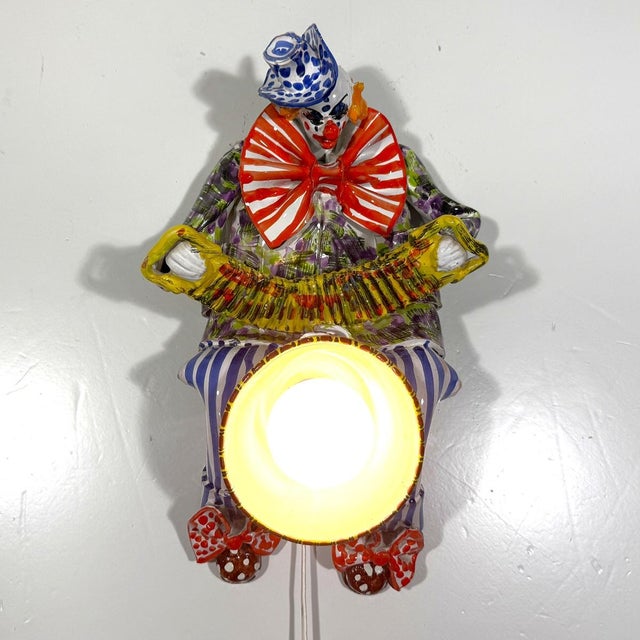 Very special ceramic wall lamp, Italy. Ceramic colorful clown that holds a flowerpot with light in it. Steel wall...
