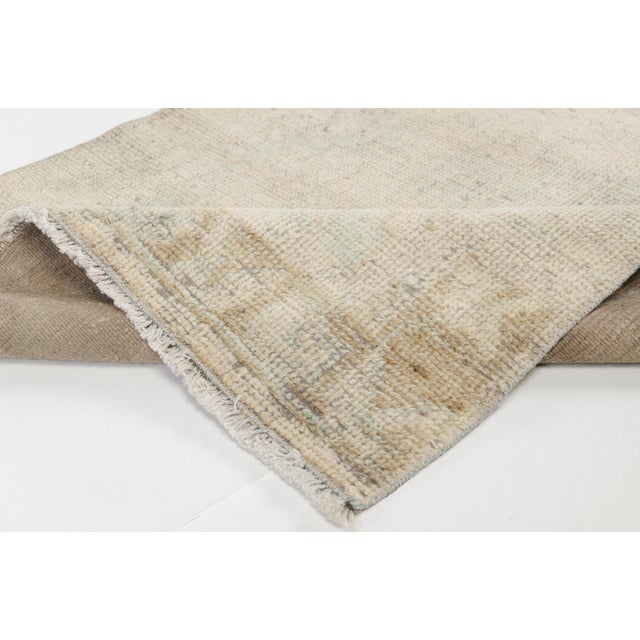 This is a vintage Turkish Oushak rug from the Mid 20th Century. The piece was hand-knotted.