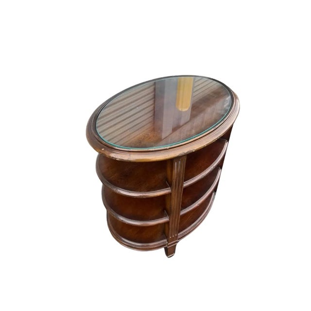 This accent table has a glass top and three shelves and is solid wood. It’s a transitional style that would go with any...