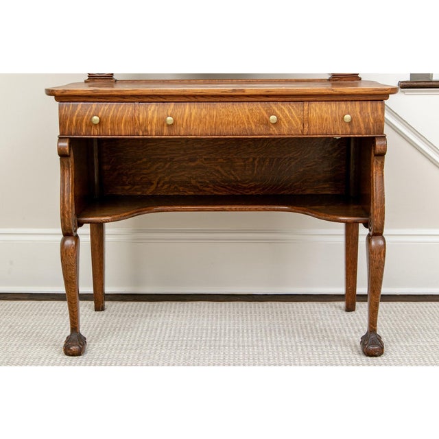 An early 20th century wooden vanity dressing table with an oval tilting mirror in a carved frame mounted on decoratively...