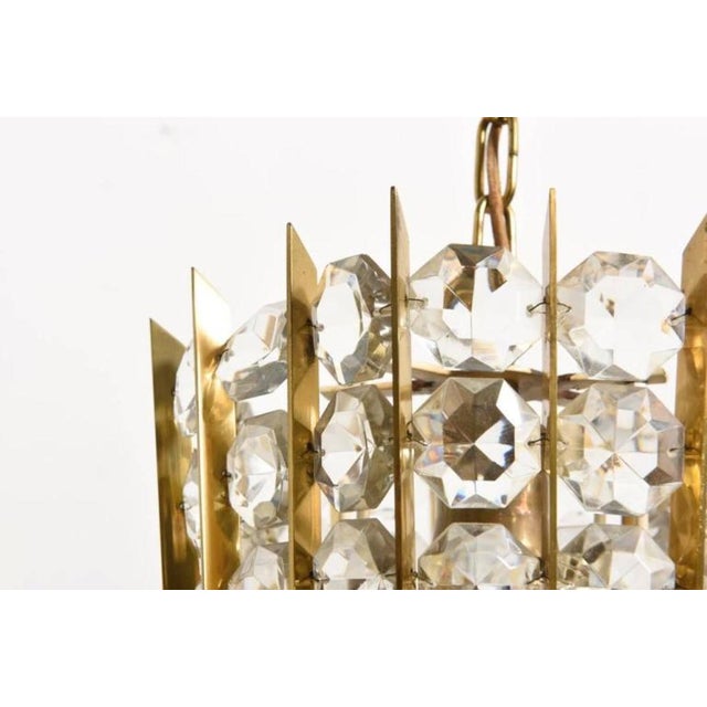 This chandelier has a brass construction that holds faceted diamond shaped crystals and was produced by Bakalowits &...
