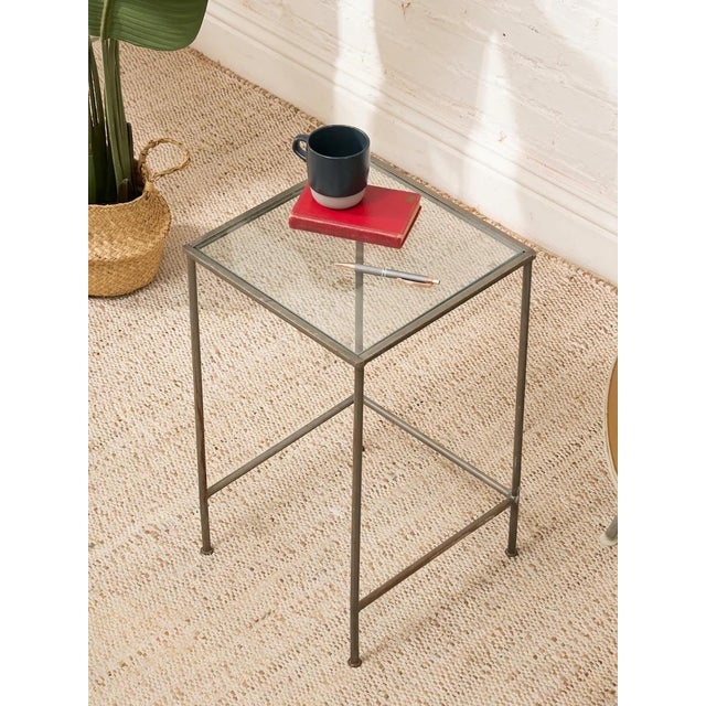 A streamlined vintage bar table with a tall, architectural metal frame and a square clear glass top. The slender...