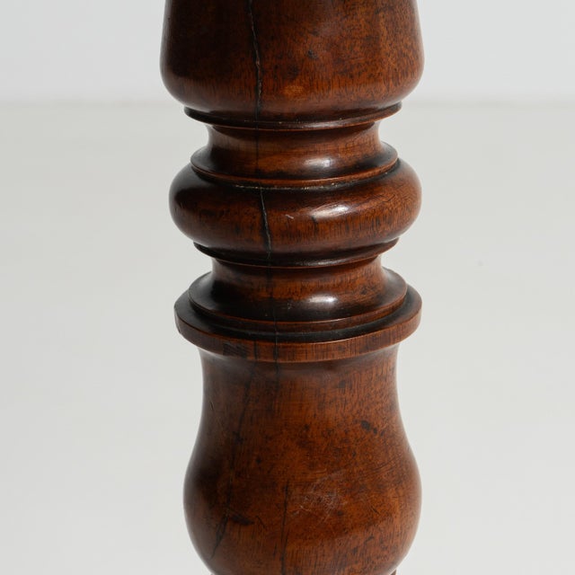 A circa 1900 French side table crafted in wood with an inlaid circular top supported by a pedestal base. The design...