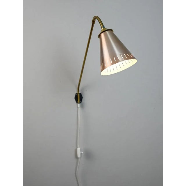 Scandinavian manufacturing direct wall lamp. This piece of vintage Swedish design consists of a golden metal arm and a...