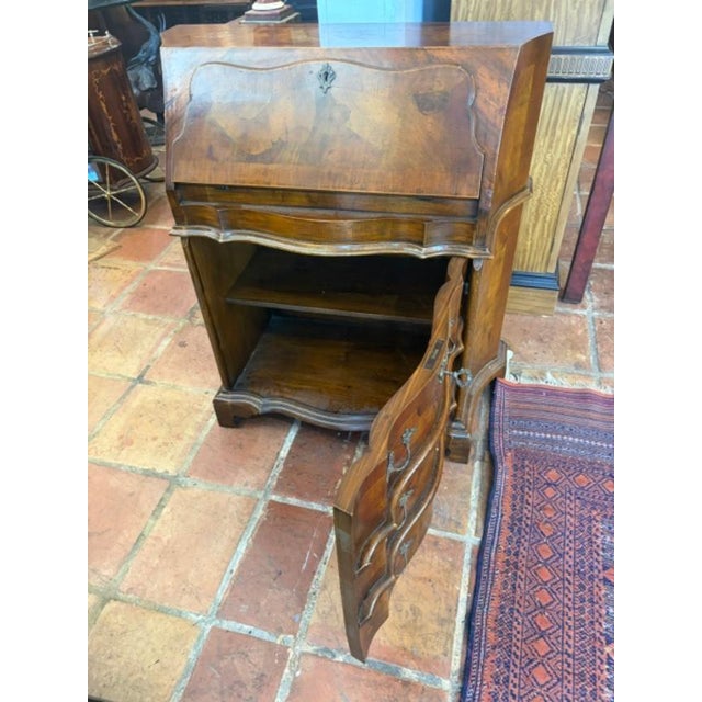 The Italian 1920s Walnut & Burl Wood Diminutive Drop Front Desk is a charming antique piece with a classic brown color and...